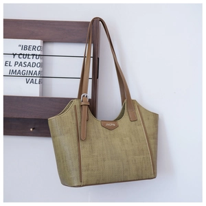 Detail of olive green tote bag featuring woven texture and brown leather strap on rack