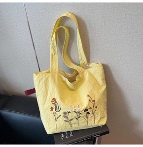Detailed close-up of delicate floral embroidery on yellow canvas tote bag