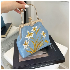 Close-up of floral embroidery and gold metal frame on a retro blue canvas handbag