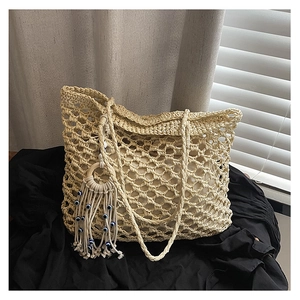 Close-up of beige woven tote bag with evil eye tassel and detailed mesh crochet pattern