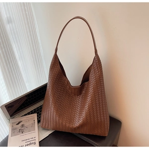 Detail of a brown woven leather tote bag featuring a classic checkerboard pattern