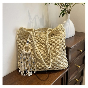 Detail of hollow woven beach tote with bohemian tassel and blue evil eye charms