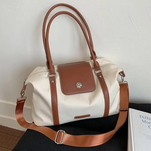 Detail view of large travel tote with white nylon body and brown leather handles and strap