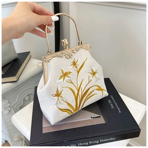 Close-up of vintage cream canvas bag with floral embroidery and golden kiss-lock clasp