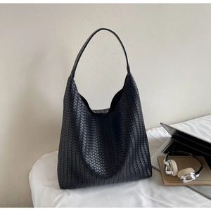Detail of black woven leather tote with intricate Intrecciato texture and sleek strap
