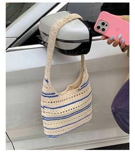 Detail of crochet tote bag in cream and blue stripes hanging on a mirror outdoors