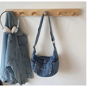 Detail of vintage denim crescent bag with multi-zipper pockets and frayed fringe tassels