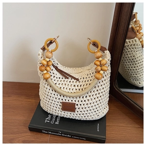 Détail du sac seau tissé crème avec perles en bois et étiquette logo en cuir marron