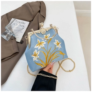 Detail of vintage blue canvas bag with exquisite floral embroidery and golden metal frame