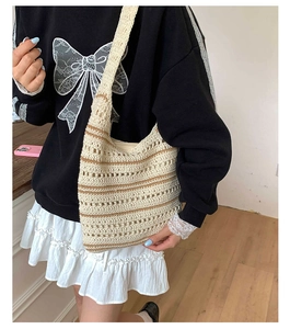 Detail of hand-woven hobo bag with beige cotton texture and brown striped hollow pattern