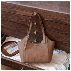 Detail of vintage brown tote bag texture and leather label inside a wooden drawer