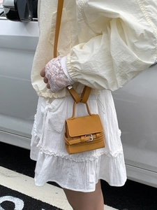Mustard yellow mini square handbag with top handle and crossbody strap on model