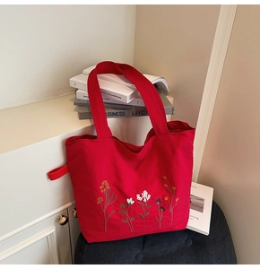 Close-up of red canvas tote bag with intricate floral embroidery and textured fabric