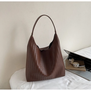 Detail of dark brown woven tote bag next to a laptop showing refined craftsmanship