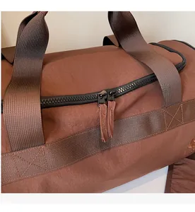 Détail des fermetures éclair noires et des poignées brunes d'un sac de sport voyage