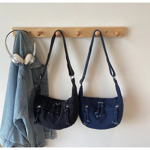 Detail of denim crescent bags in black and blue with multiple fringe zipper pockets