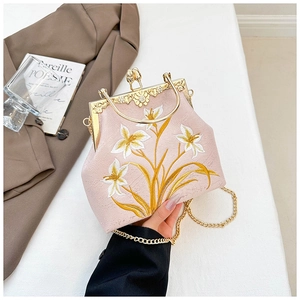 Close-up of pink satin bag with elegant lily embroidery and gold metal chain strap