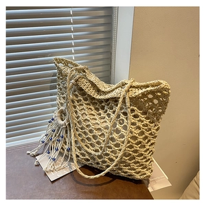 Detail of hand-woven tote bag showing mesh texture and Evil Eye tassel charm