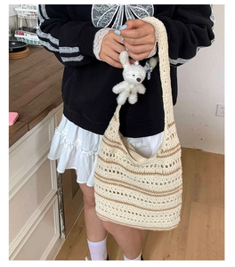 Detail of a beige knit shoulder bag with brown stripes and a cute plush rabbit charm