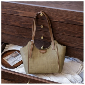 Detail view of woven khaki texture and leather accents on a vintage tote bag