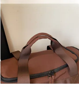 Détail du sac de voyage marron montrant des poignées renforcées et des zips doubles robustes