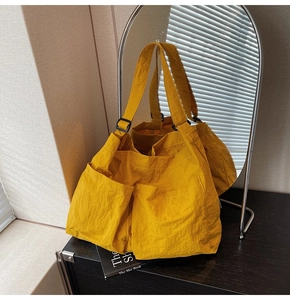 Detail view of large yellow tote bag with dual front pockets and adjustable strap