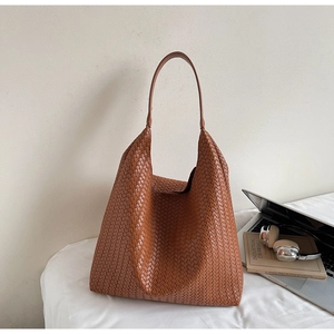 Brown woven leather hobo shoulder bag styled with laptop and books for work commute