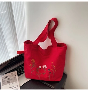 Detail view of colorful floral embroidery on a durable red canvas tote bag