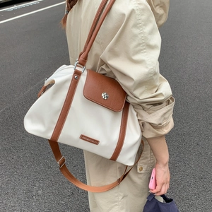 Detail of travel bag side capacity with adjustable brown shoulder strap on model
