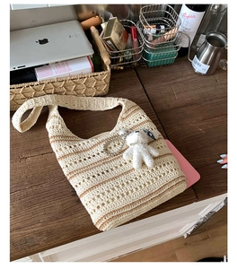 Detail of cream woven tote bag with brown stripes and a cute plush bear charm accessory