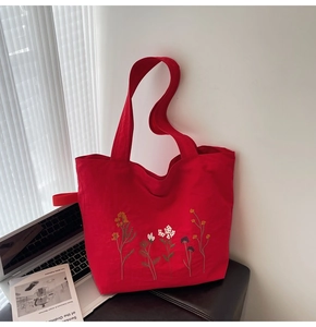 Close-up of vibrant red canvas tote bag with intricate floral embroidery details