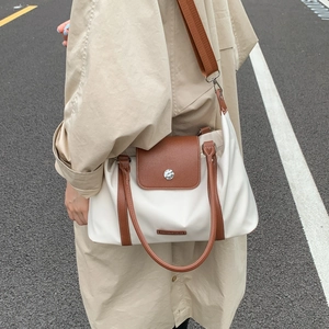 Nylon travel tote with leather handles and strap shown in real-world outdoor usage