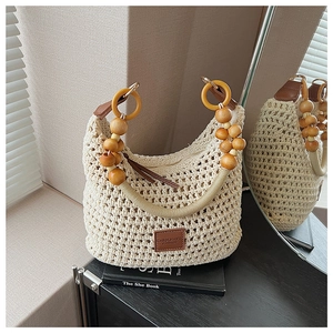 Détail du sac seau tissé avec poignée en perles de bois et étiquette en cuir