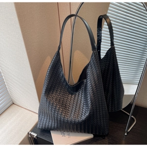 Detailed mirror view of a black woven leather hobo tote bag featuring intricate craftsmanship