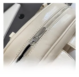 Detail shot of high-quality silver metal zipper and buckle on cream oil wax leather bag