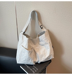 Detail of beige tote bag featuring pleated texture fabric and large front pockets