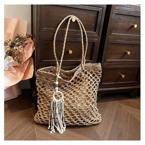 Detail of hollow woven straw tote bag with evil eye tassel charm and cloth lining