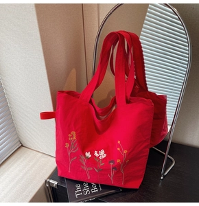 Detail of vibrant red canvas tote bag featuring intricate colorful floral embroidery