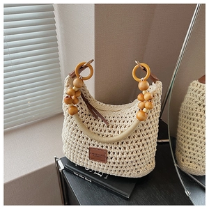 Détail du sac seau beige en maille ajourée avec poignée en perles de bois et logo