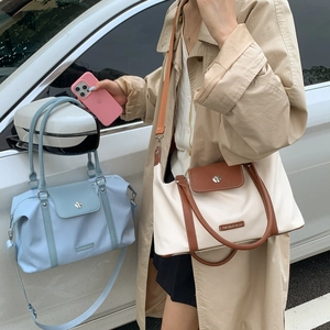 Detail of nylon travel duffel bags in light blue and beige with leather handles and straps