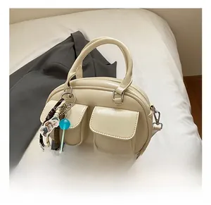 Detail view of cream vintage pillow bag with dual front pockets and cute bear charm