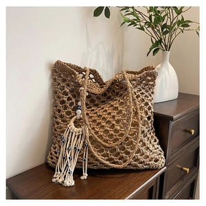 Detail of hollow woven beach tote with bohemian tassel and blue evil eye charm