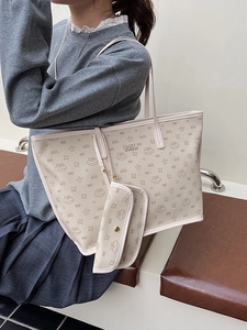Beige tote bag with cartoon print and small coin purse shown from a side shoulder view