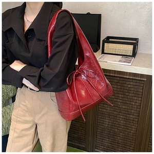 Close-up of wine red oil wax leather tote bag with glossy finish and bow tie detail