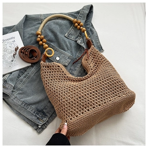 Détail d'un sac seau tissé kaki avec poignées en perles de bois sur veste en jean