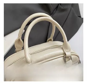 Detail showing soft textured cream leather handle and silver metal hardware of the bag