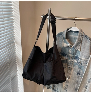 Detail of durable black nylon tote bag featuring large front pockets and adjustable strap
