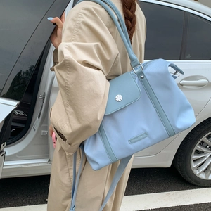 Detail of light blue nylon travel bag with side flap pocket and silver metal buckle