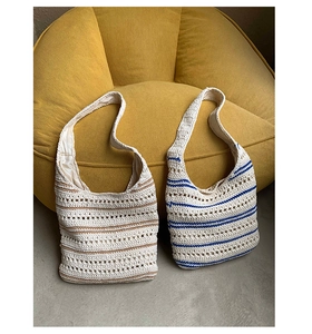 Detail view showing hand-knitted cotton texture and brown-blue stripes on a tote bag