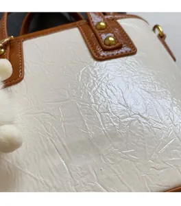 Detail of soft pleated cream fabric with gold rivets and brand logo on a bucket bag